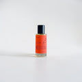 Amber Love Body Oil — bright orange, leafy greens, wild cherry, jasmine, freesia, rose, honeysuckle, sandalwood, and warm musk photographed on a clean white background.