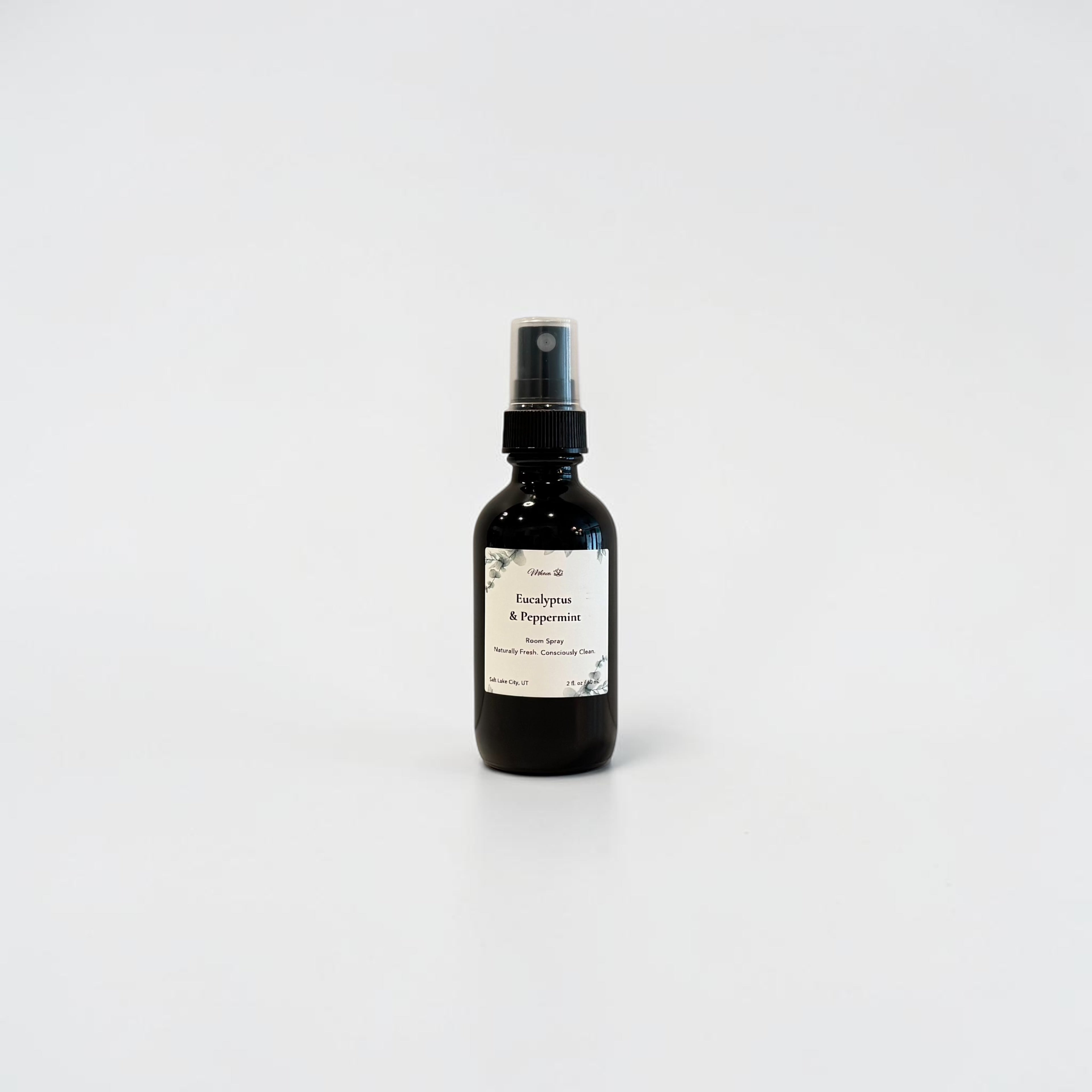 Eucalyptus & Peppermint 2oz Essential‑Oil Room Spray — black glass bottle with a clean minimalist label, infused with natural eucalyptus essential oil and peppermint essential oil, styled on a light surface in soft natural light.